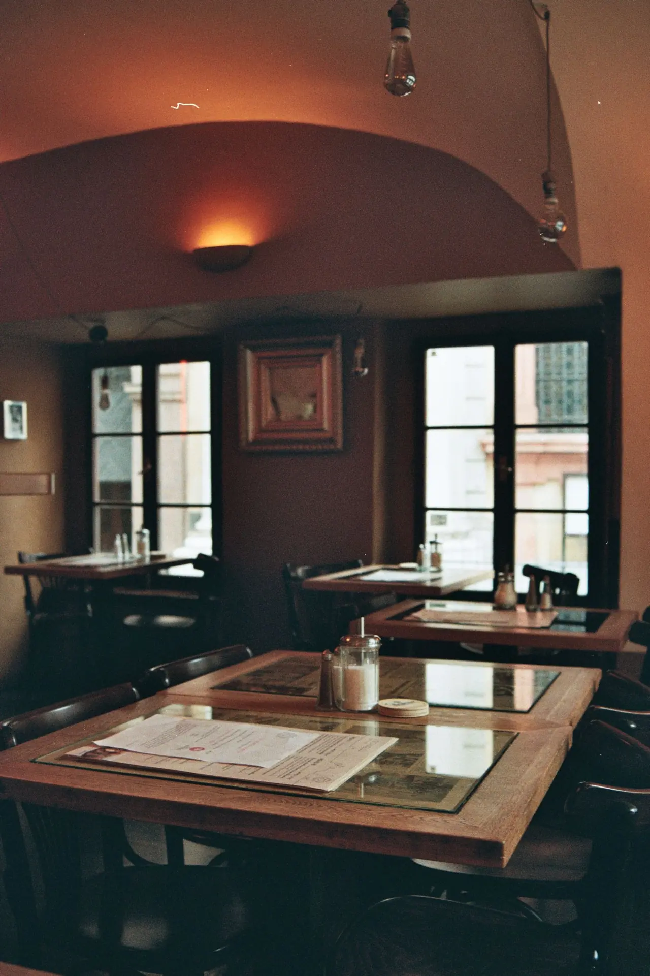 Salle de restaurant avec tables près de fenêtres et murs colorés.